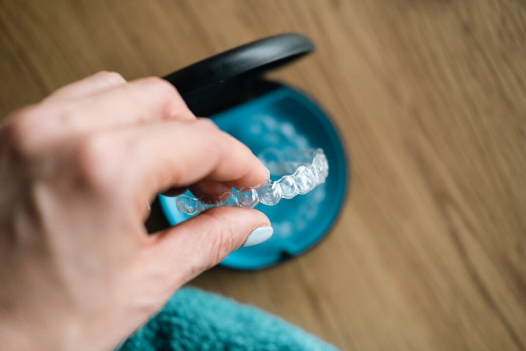 Close up of a woman holding an invisible aligner, ready to put it in its case