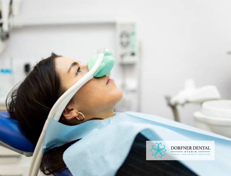 A patient receiving nitrous oxide sedation in a dental chair, with the Dorfner Dental Studio logo in the corner.