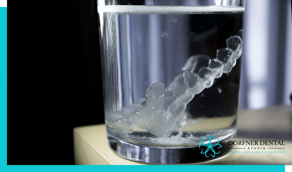 Invisalign aligners soaking in a glass of water