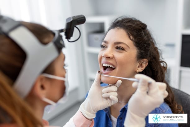 Dentist examining a female patient’s teeth with dental tools during a consultation at Dorfner Dental Studio