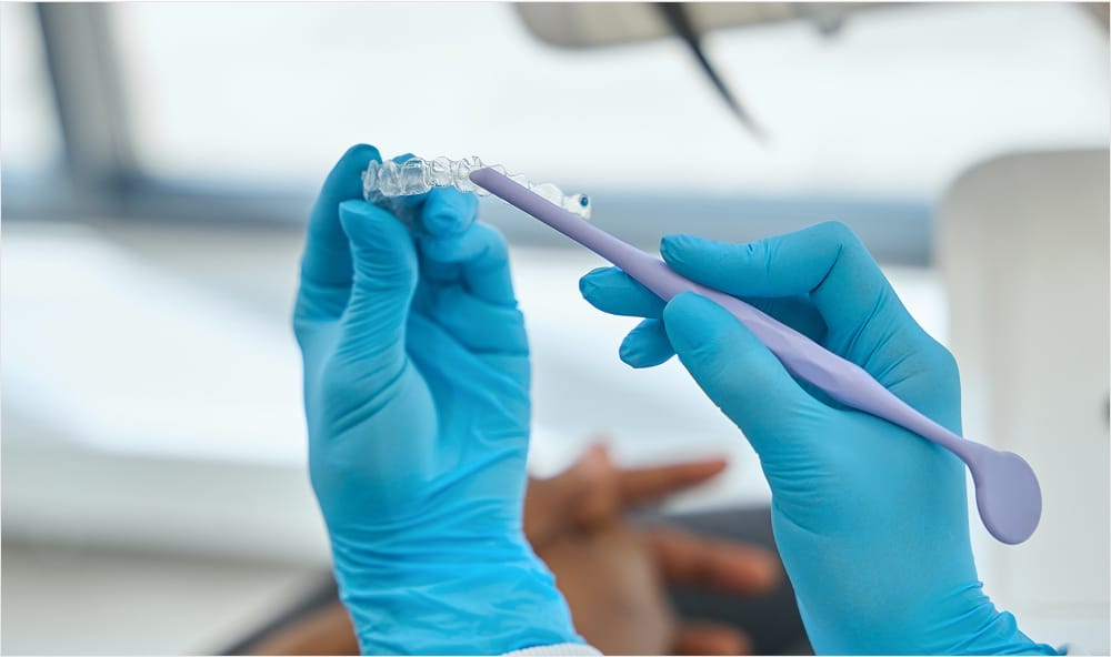 Gloved hand holding and examining Invisalign aligners