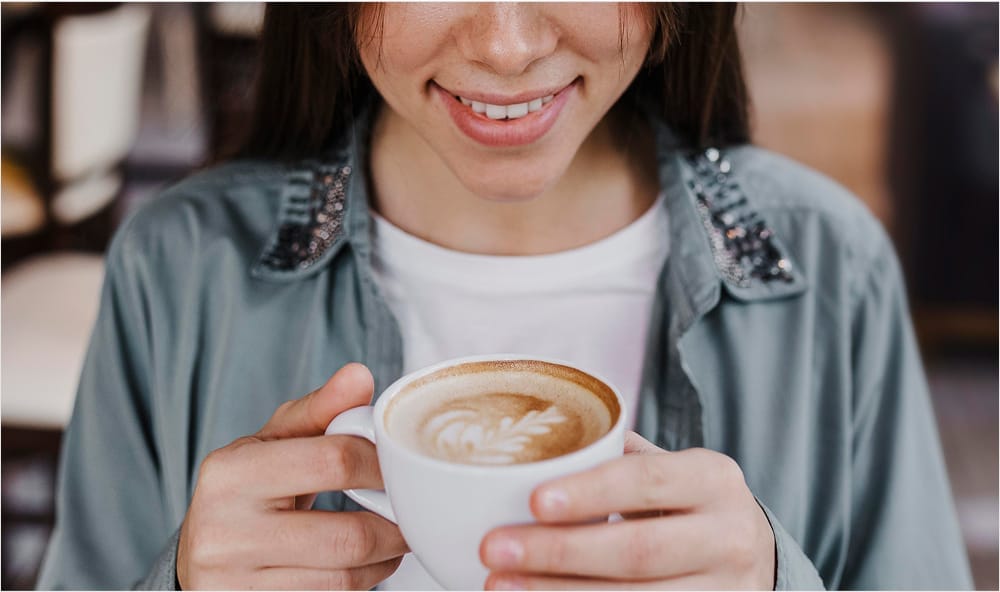 Woman holding a coffee mug near her lips, preparing to drink