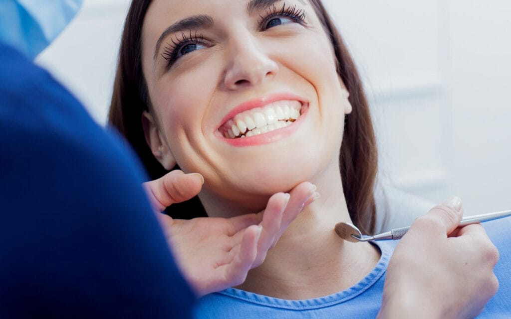 Smiling female patient during dental checkup, happy with her healthy white teeth