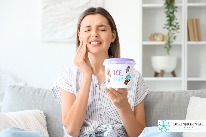 Woman experiencing tooth sensitivity and pain while holding ice cream.